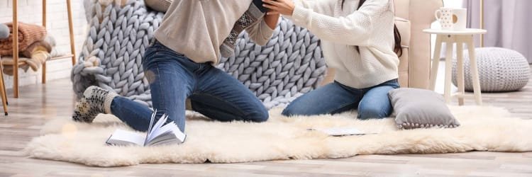 couple sitting and playing on off-white area rug